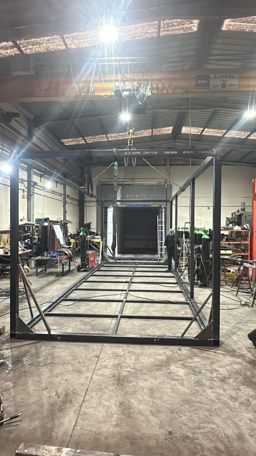 Chasis de acero de una caseta modular en el taller, bajo la grúa puente, antes de montar paredes y suelo